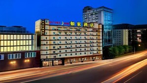 A hotel with multiple floors, a prominent sign, and a modern building adjacent to it. - Home Inn (Heyuan Railway Station) (Heyuan)