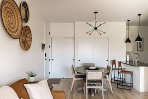 A modern kitchen with a dining area, featuring a round table, chairs, and a pendant light.