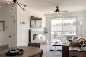 A modern living room with a fireplace, a dining table, and a sofa.