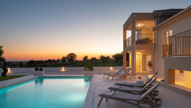 A modern poolside area with a clear view of the sunset, a pool, and lounge chairs. - Luxury Villa Morus with pool 50m2, gym, family, bbq (Murvica)