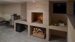 A modern living room with a built-in fireplace, a dining area with chairs, and a small kitchen area. - Luxury Villa Morus with pool 50m2, gym, family, bbq (Murvica)