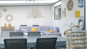 Un rincón de comedor con una mesa y sillas, un sofá con cojines y decoración en la pared.