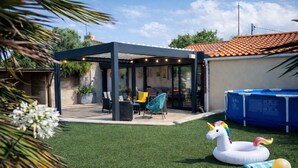 Un patio cubierto con mobiliario exterior, una piscina y un juguete inflable de unicornio.