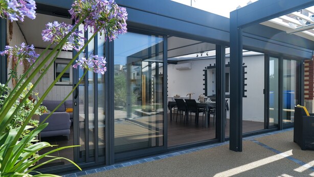 Una casa moderna con amplios ventanales que dan a un patio.