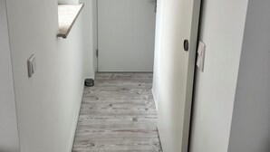 A narrow hallway with a wooden floor, white walls, and a door at the end. - Krefeld Ruhiges Apartment in der 2. Etage. Mit Klimaanlage (Krefeld)