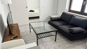 A modern living room with a glass coffee table, a dark grey sofa, and a wooden side table. - Krefeld Ruhiges Apartment in der 2. Etage. Mit Klimaanlage (Krefeld)