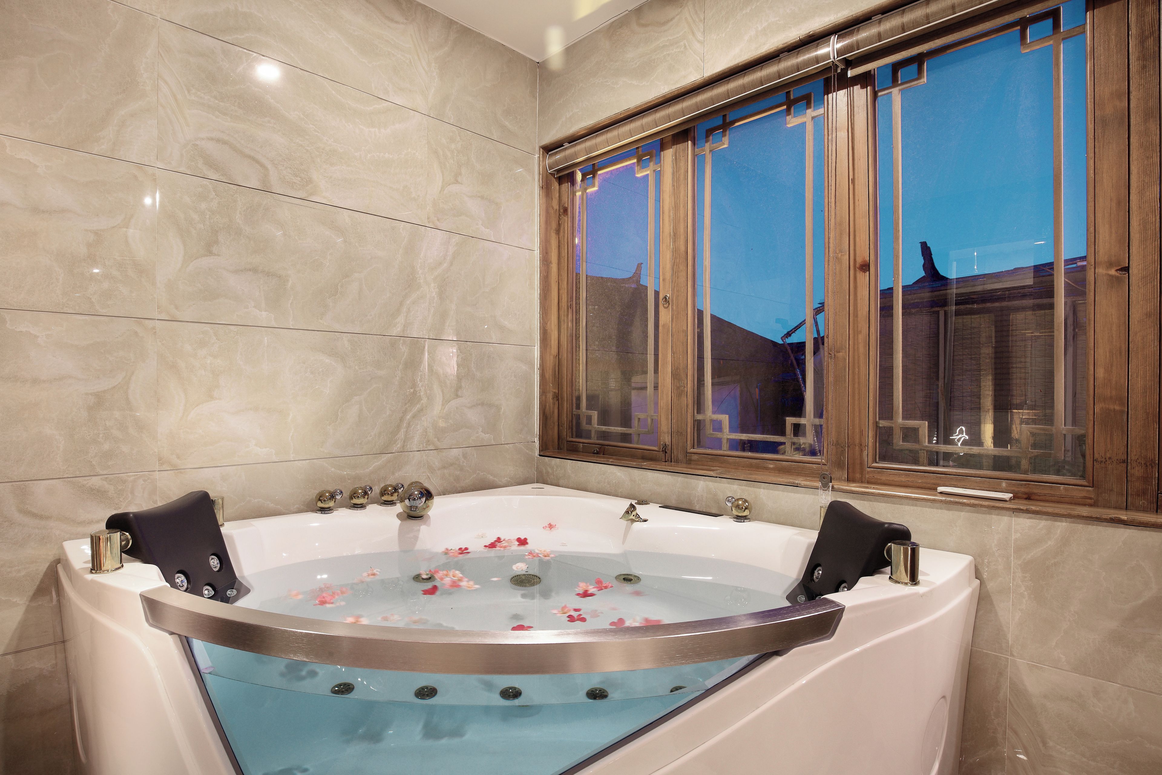 A bathroom with a freestanding bathtub, a window with wooden frames, and a marble wall.