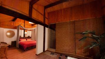 Una habitación de madera tradicional con una cama, un panel tejido y una planta grande.