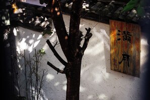 A tree in front of a wall with a traditional Chinese character sign. - Full moon Inn Lijiang (Lijiang)