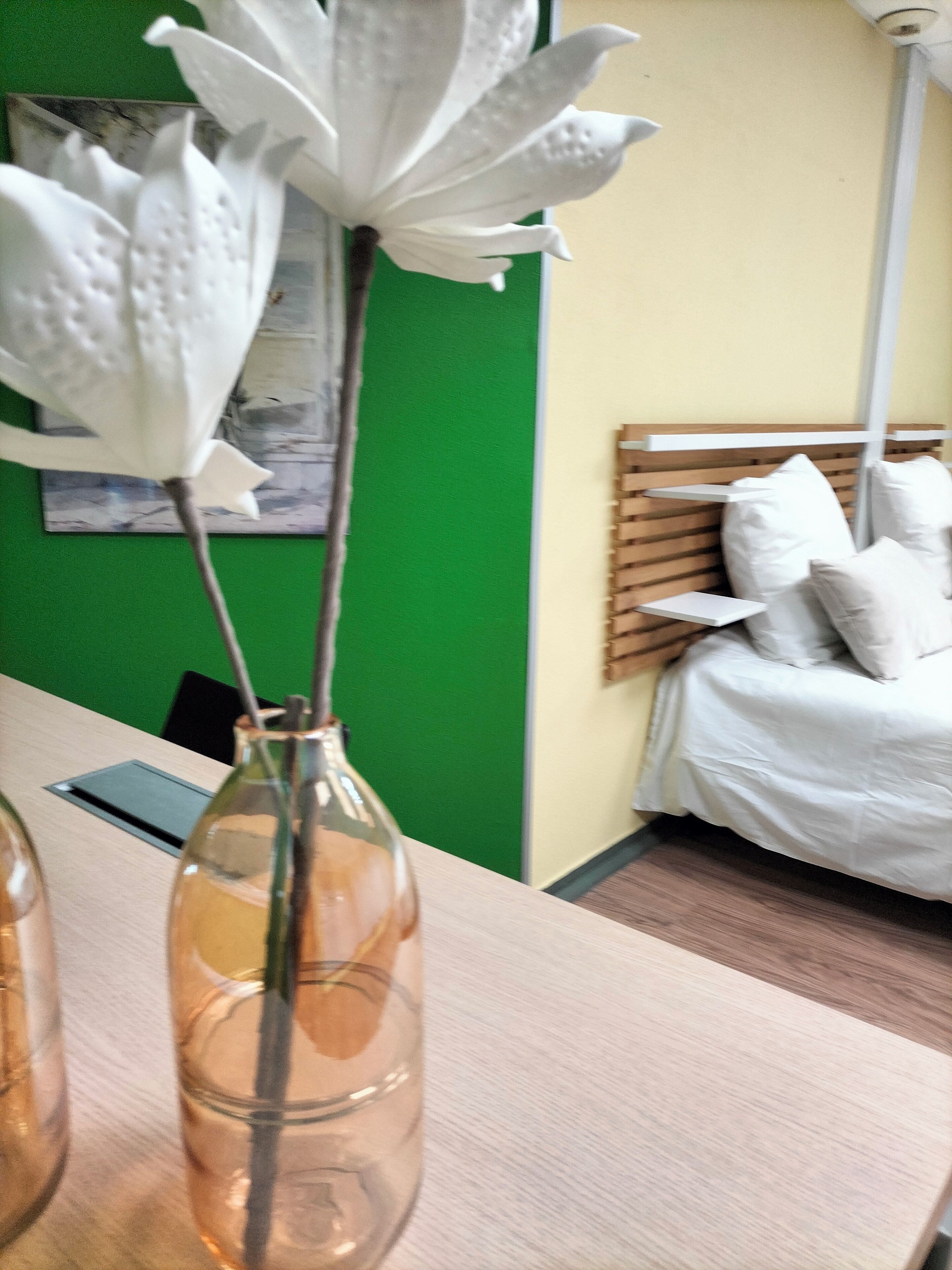 Ein Zimmer mit einem Bett, einer grünen Wand und einem hölzernen Kopfteil.