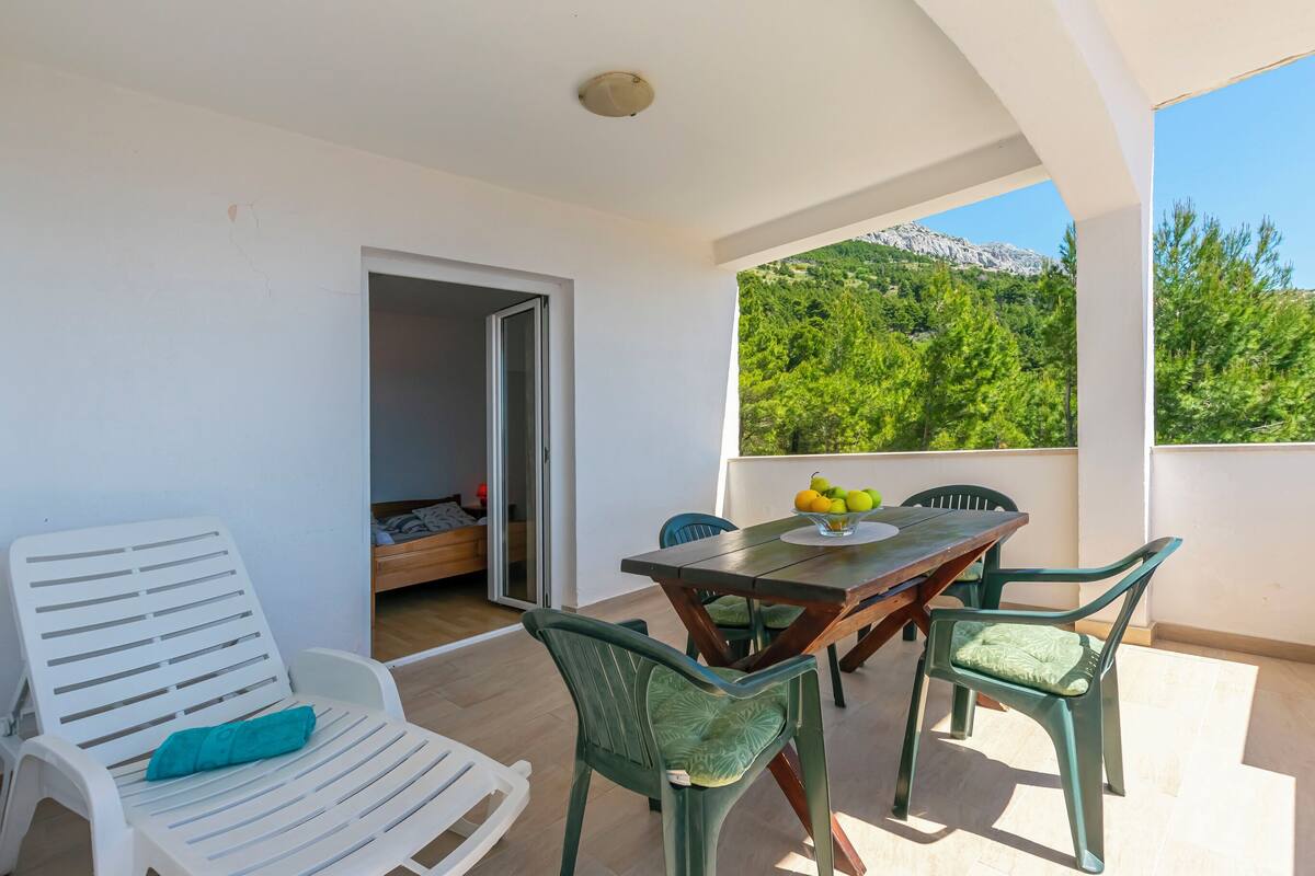 A balcony with a table, chairs, and a view of a mountain.