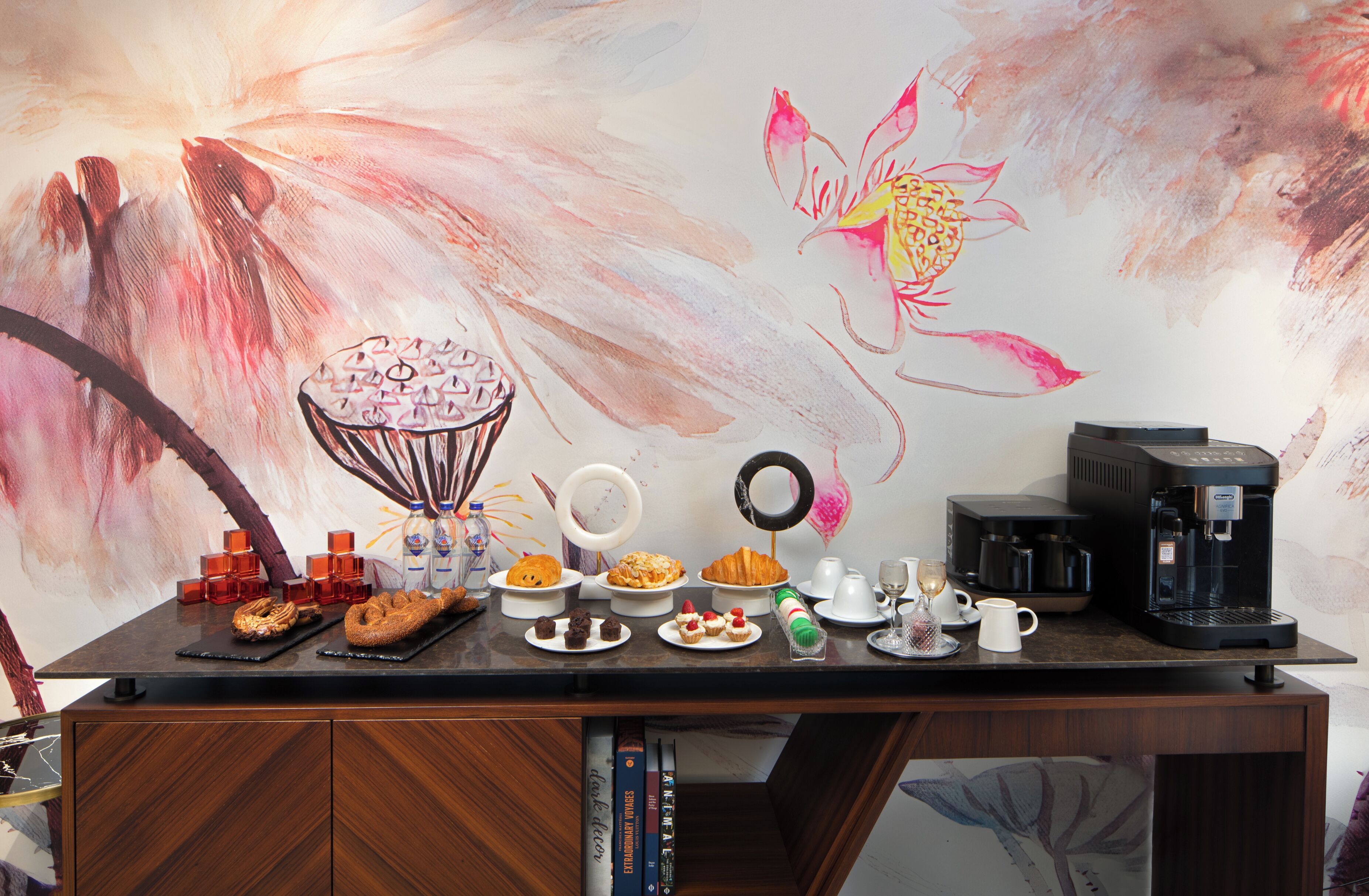 A bar area with a coffee machine, various drinks, and pastries on a counter.