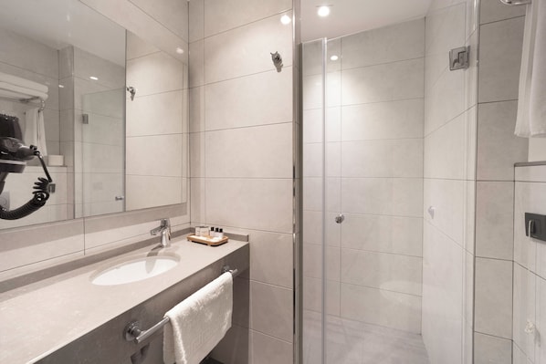 A modern bathroom with a large mirror, two sinks, and a glass shower enclosure. - Ess Hotel (Istanbul)