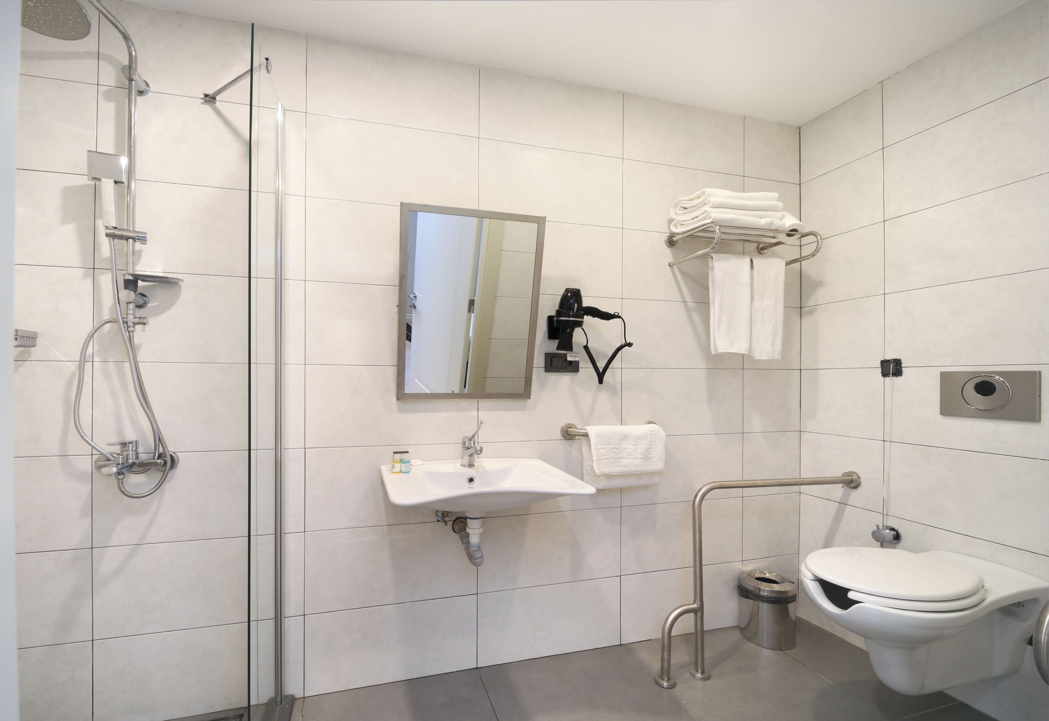 A modern bathroom with a shower, sink, toilet, and a towel rack.