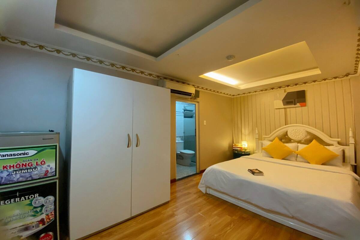 Una habitación de hotel con cama, armario blanco y un refrigerador Panasonic.