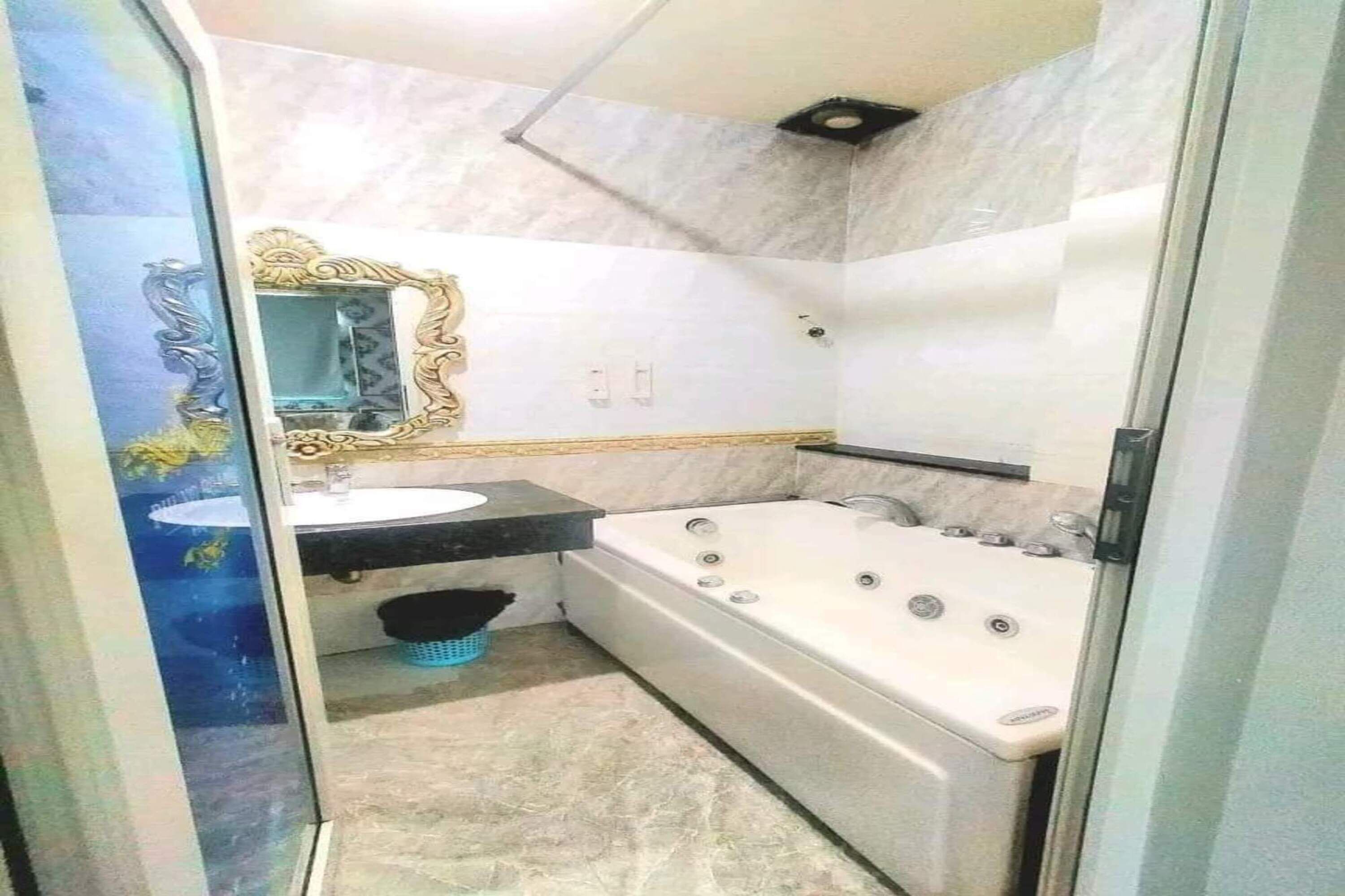 A bathroom with a white bathtub, a sink, and a mirror with an ornate frame.