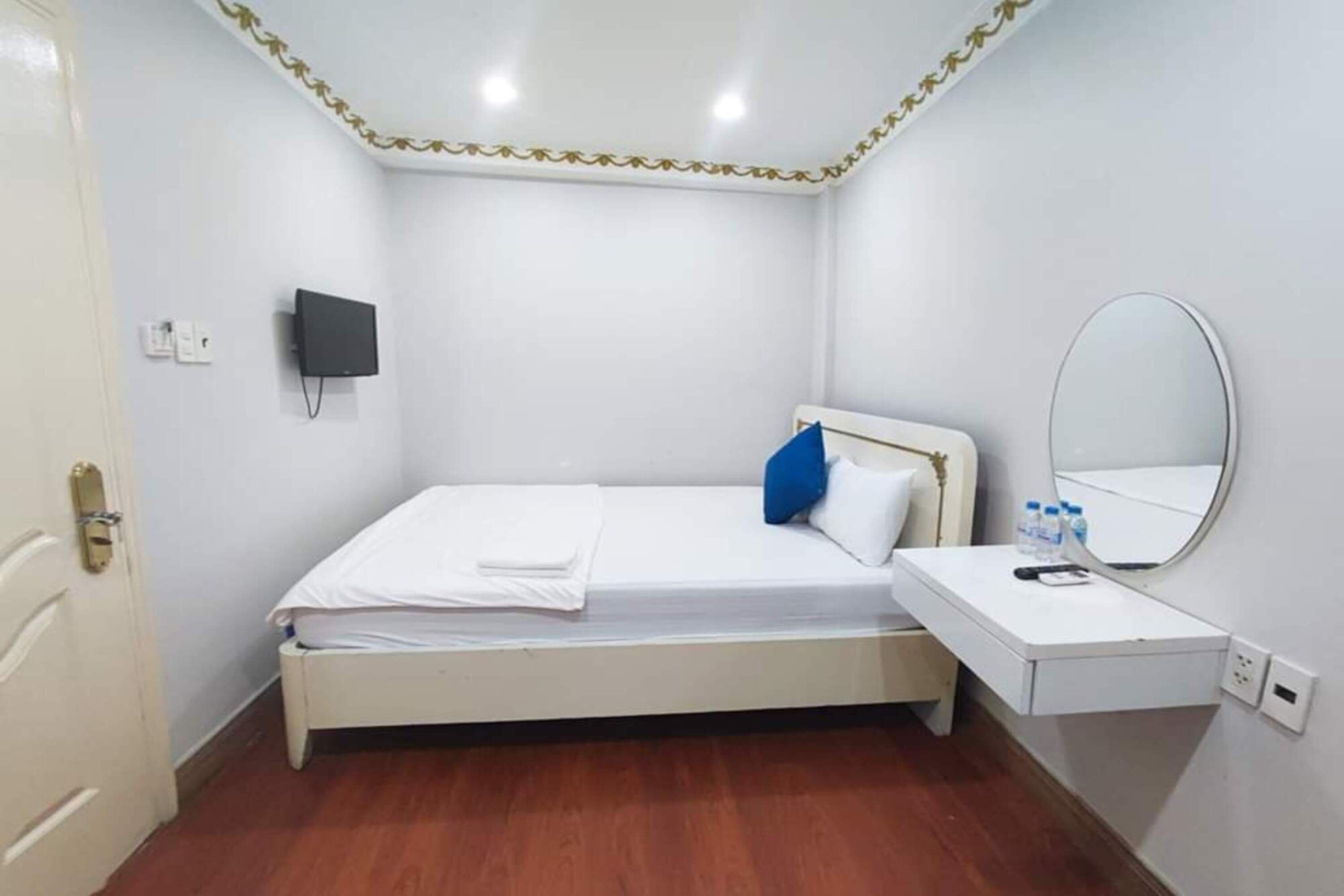 Ein Schlafzimmer mit Bett, Nachttisch und einem am Wand montierten Fernseher.