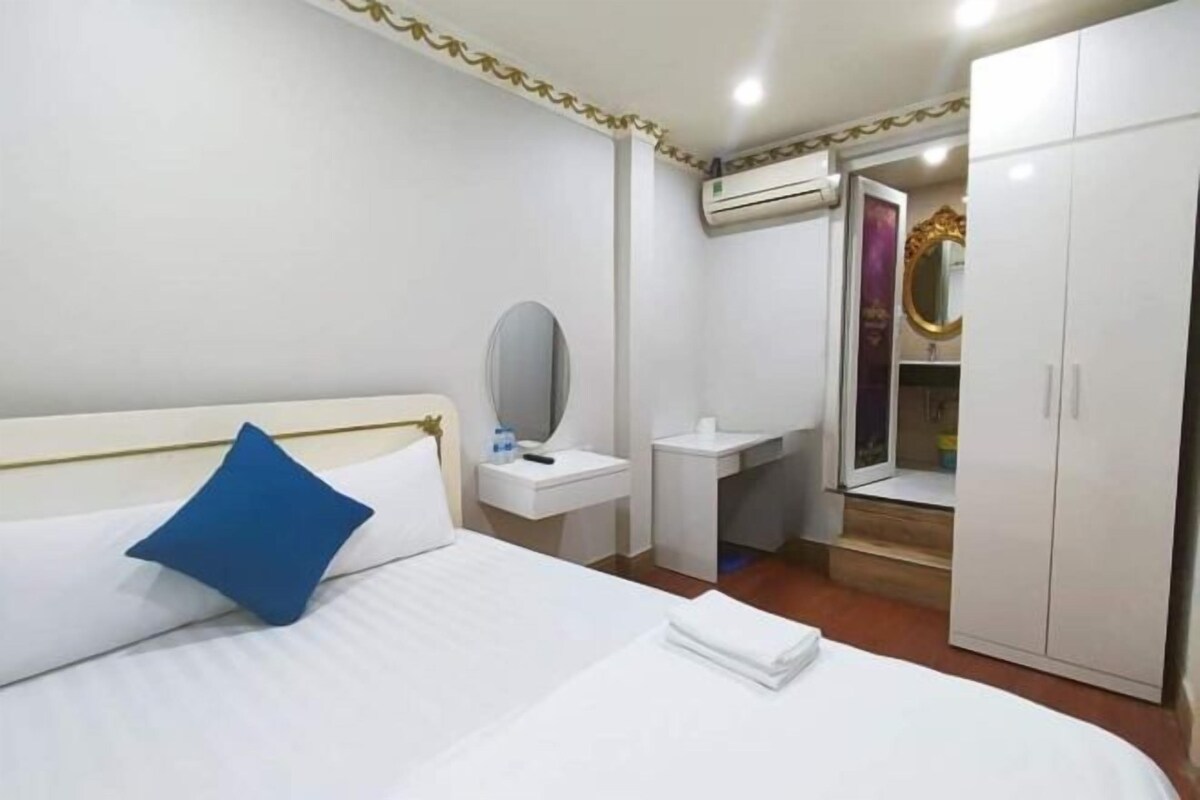 Habitación de hotel con cama, mesita de noche, espejo, armario y aire acondicionado.