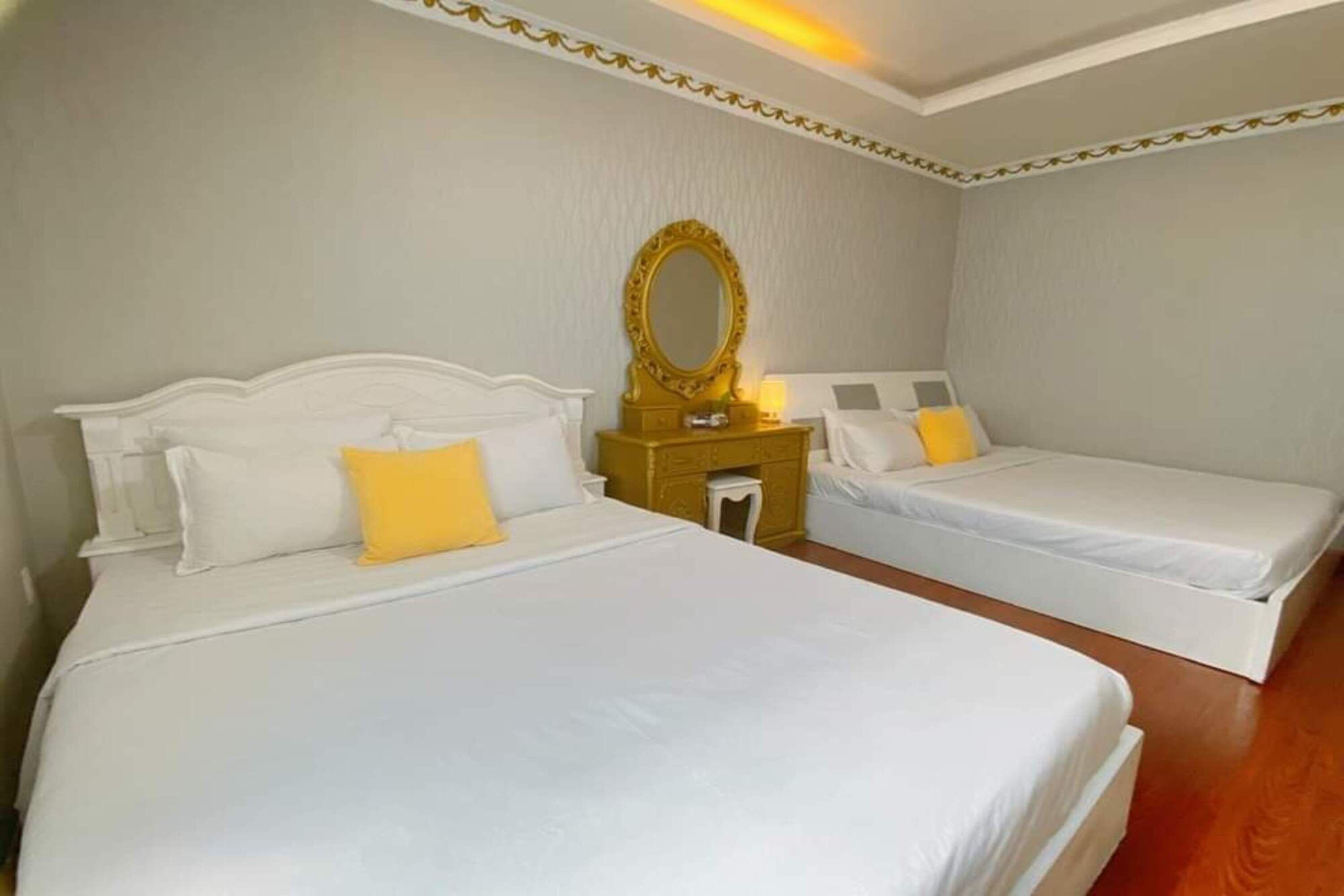 Una habitación de hotel con dos camas individuales, una mesita de noche pequeña con lámpara y un espejo grande en la pared.