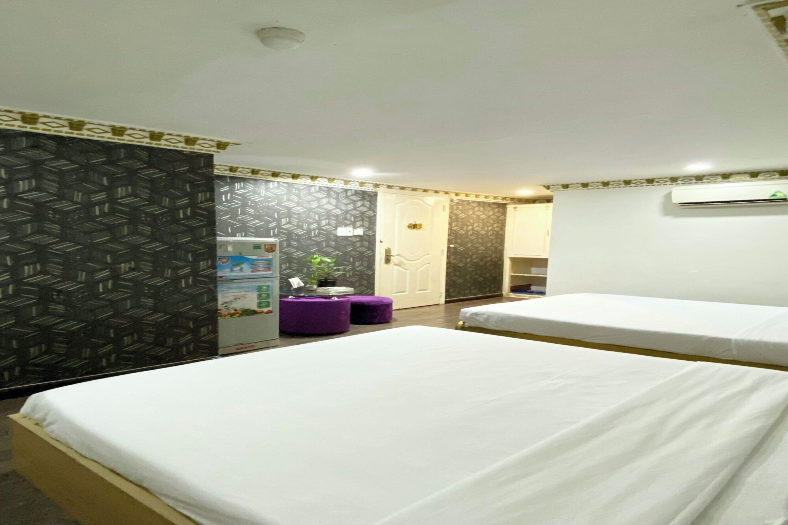 Een hotelkamer met twee bedden, een kleine kitchenette, een badkamer en een kamer met een patroon op de muur.
