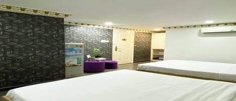 Een hotelkamer met twee bedden, een kleine kitchenette, een badkamer en een kamer met een patroon op de muur.