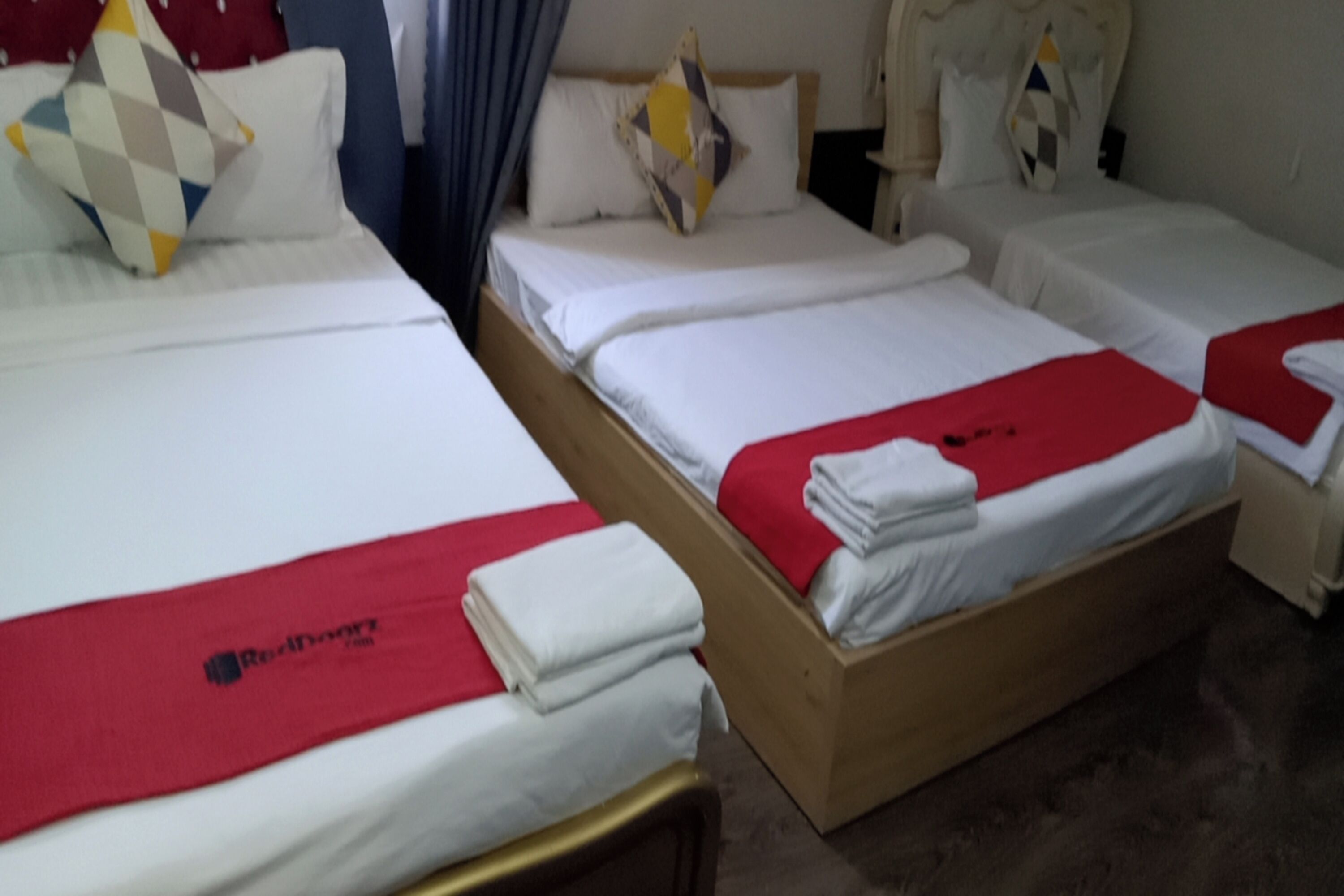 A hotel room with two single beds, each with a red blanket and white bedding.