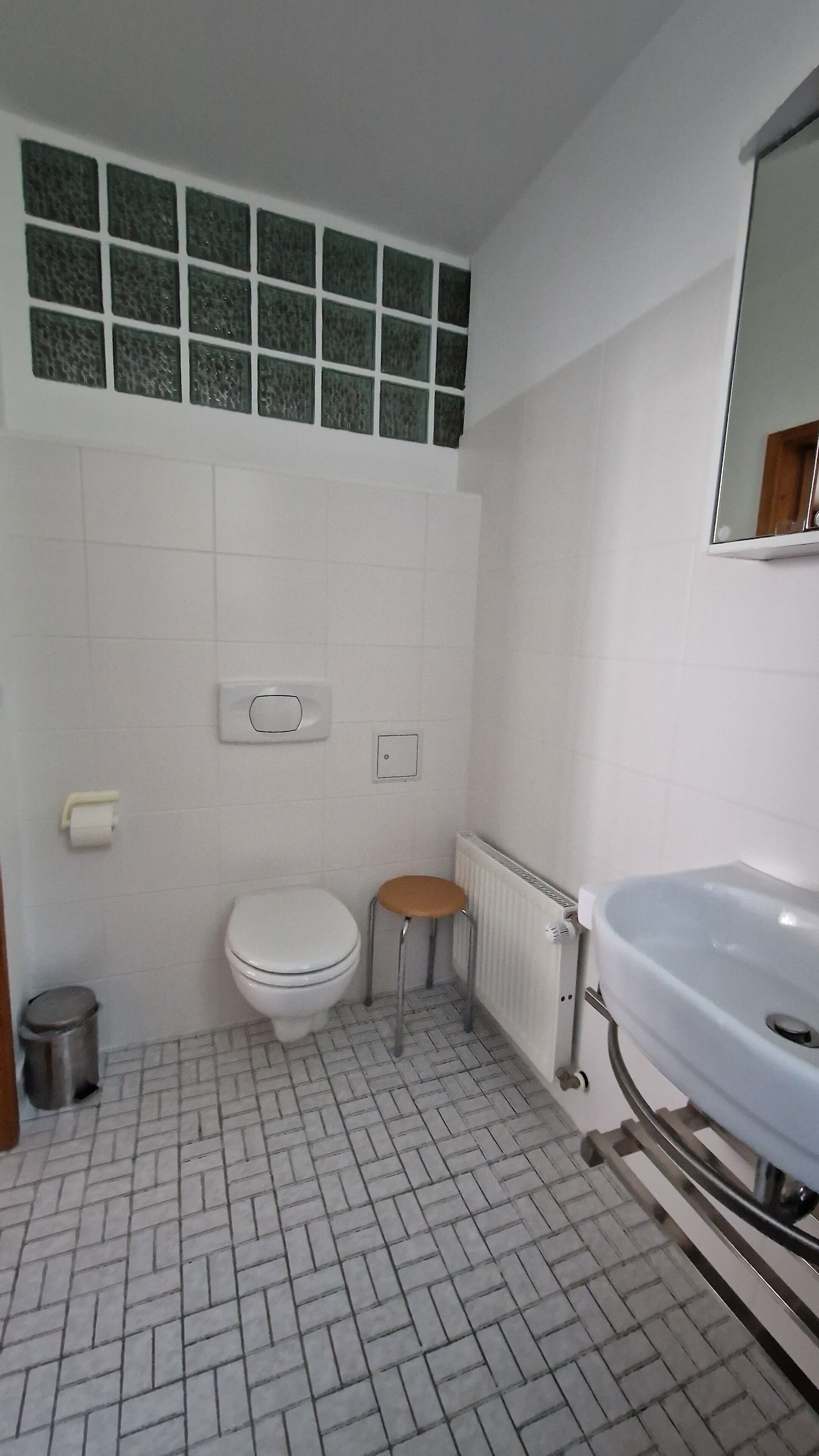 A bathroom with a toilet, a sink, a mirror, and a radiator.