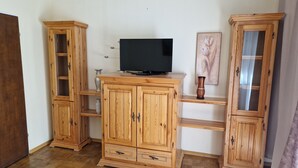Ein Zimmer mit Holzausstattung, einem Flachbildfernseher und einer Vase auf einem Regal.