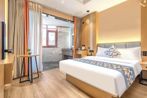 Habitación de hotel moderna con una cama grande, una mesita de noche y vistas al exterior a través de una ventana con cortinas.