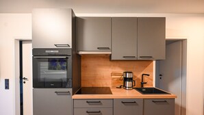 A compact kitchen with a built-in oven, a coffee maker, and a sink. - Domizil Deluxe Eleven (Kaprun)