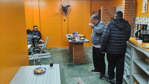 A small, enclosed dining area with a brick wall, a fan, and a table with food and drinks. - ALPHA HOSPEDARIA (Londrina)