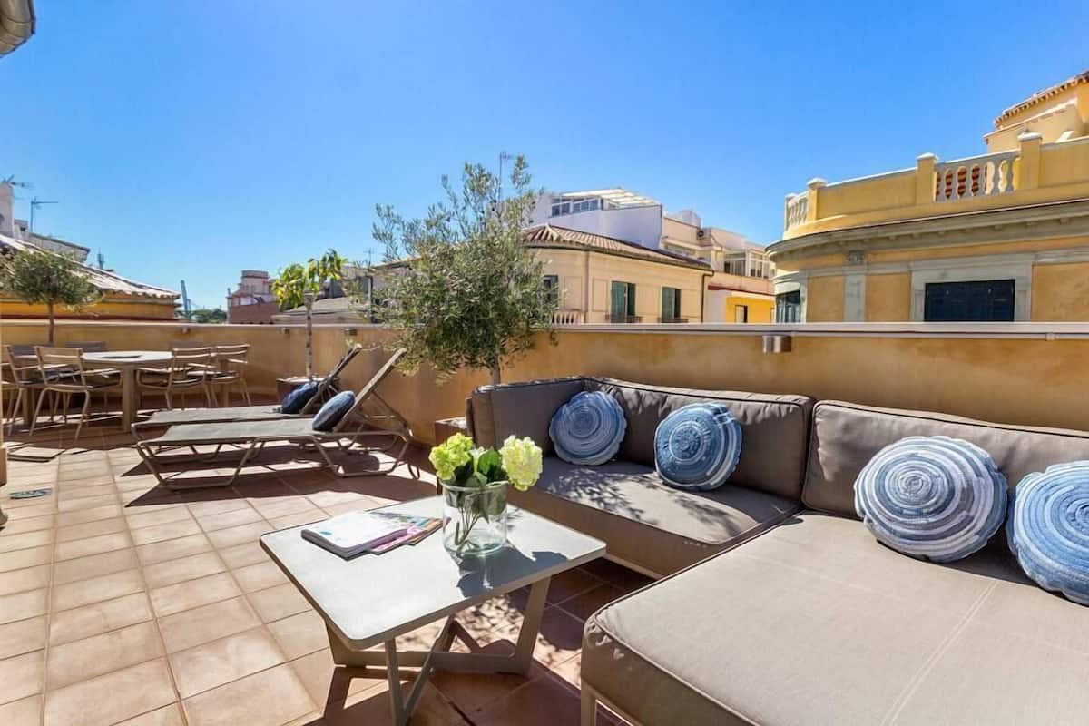 A rooftop terrace with a sofa, lounge chairs, and a table.