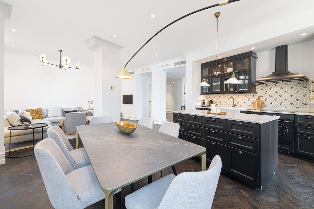 A modern kitchen with dark cabinetry, a central island, and pendant lighting.