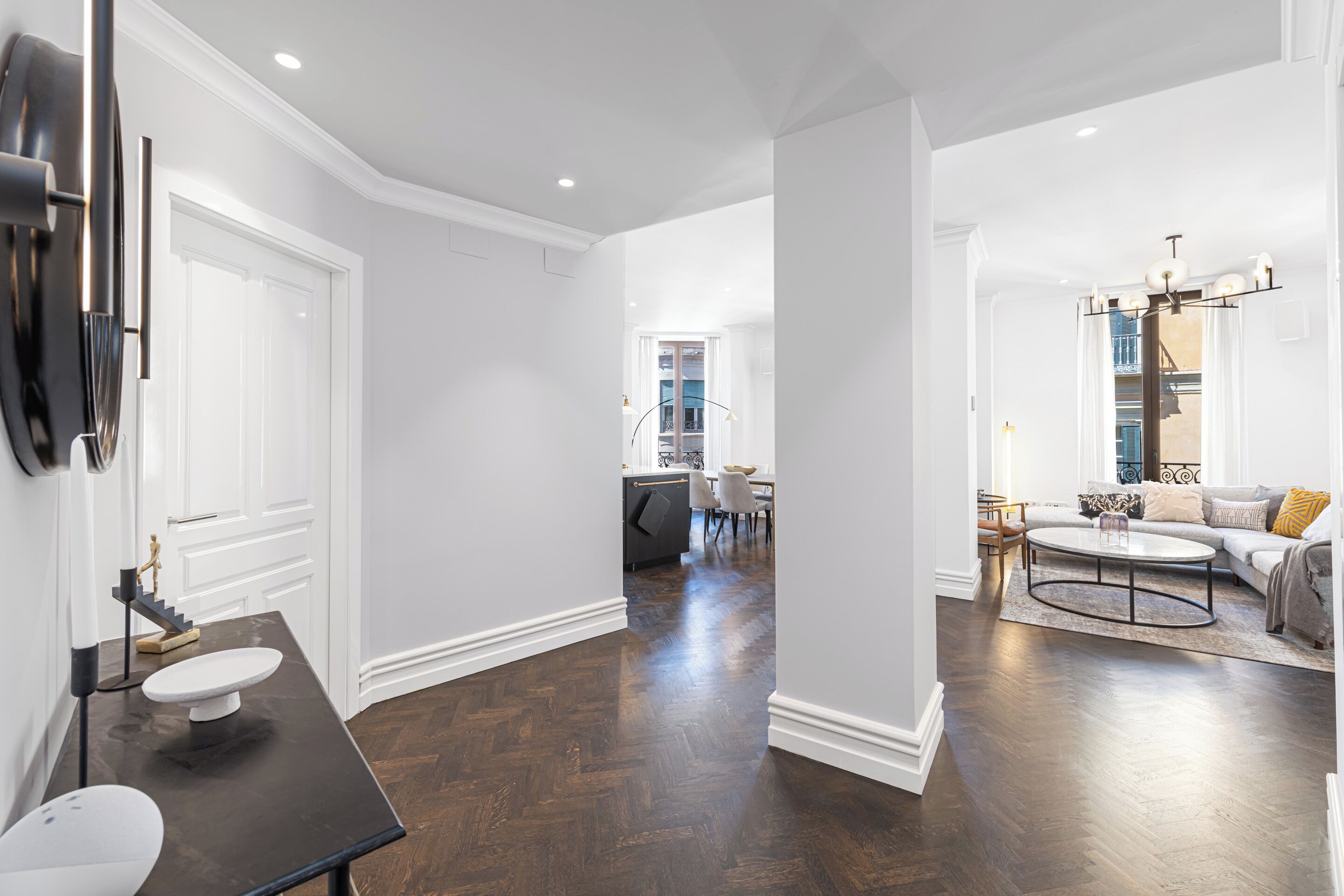 A spacious living area with a dark wood floor, a round coffee table, and a sofa with cushions.