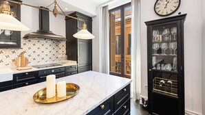 A modern kitchen with a marble countertop, black cabinetry, and a decorative clock. - Solaga Souviron Suits (Málaga)