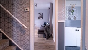 A hallway with a patterned wall, a staircase, a bed, and a bathroom with a shower curtain. - Spacious 3 Bed House, 5mins to HS2/ NEC/Airport. (Birmingham)