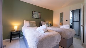 A double room with two beds, a nightstand, and a door leading to another room. - Spacious 3 Bed House, 5mins to HS2/ NEC/Airport. (Birmingham)