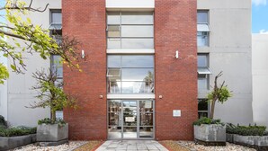 A modern building with a red brick facade, a glass entrance, and the name "MAYFAIR" above the doors. - Mayfair 246 - One Bedroom Apartment, Sleeps 3 (Cape Town)