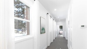 A hallway with white walls, a grey carpet, and a framed picture on the wall. - #9 New! 3 bedroom Apartment in Town (Mammoth Lakes)