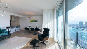 A modern living room with a sofa, a dining area with chairs, and a large window with a city view. - Vienna Residence, Donaukanal - Landstraße #6450 (Vienna)