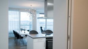 A modern kitchen with a view of the city, a dining area with chairs, and a large window with curtains. - Vienna Residence, Donaukanal - Landstraße #6450 (Vienna)