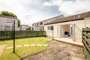 Il s'agit d'une propriété résidentielle dotée d'une cour arrière pavée, d'une terrasse en bois et d'une porte-fenêtre coulissante donnant sur l'intérieur.