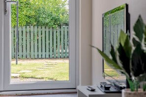 A room with a view of a green wooden fence and a grassy yard outside. - Hamilton Hideaway | St Andrews (St Andrews)