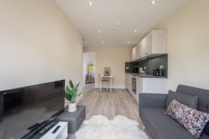 A modern living room with a flat-screen TV, a grey sofa, and a white furry rug.