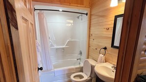 Puisilla paneeleilla verhoiltu kylpyhuone, jossa on lasiseinäinen suihku, valkoinen wc-istuin ja pesuallas.