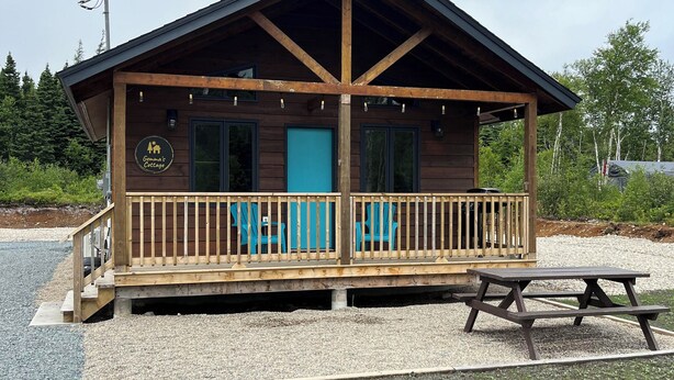 Een houten chalet met een veranda, een blauwe deur en een picknicktafel.