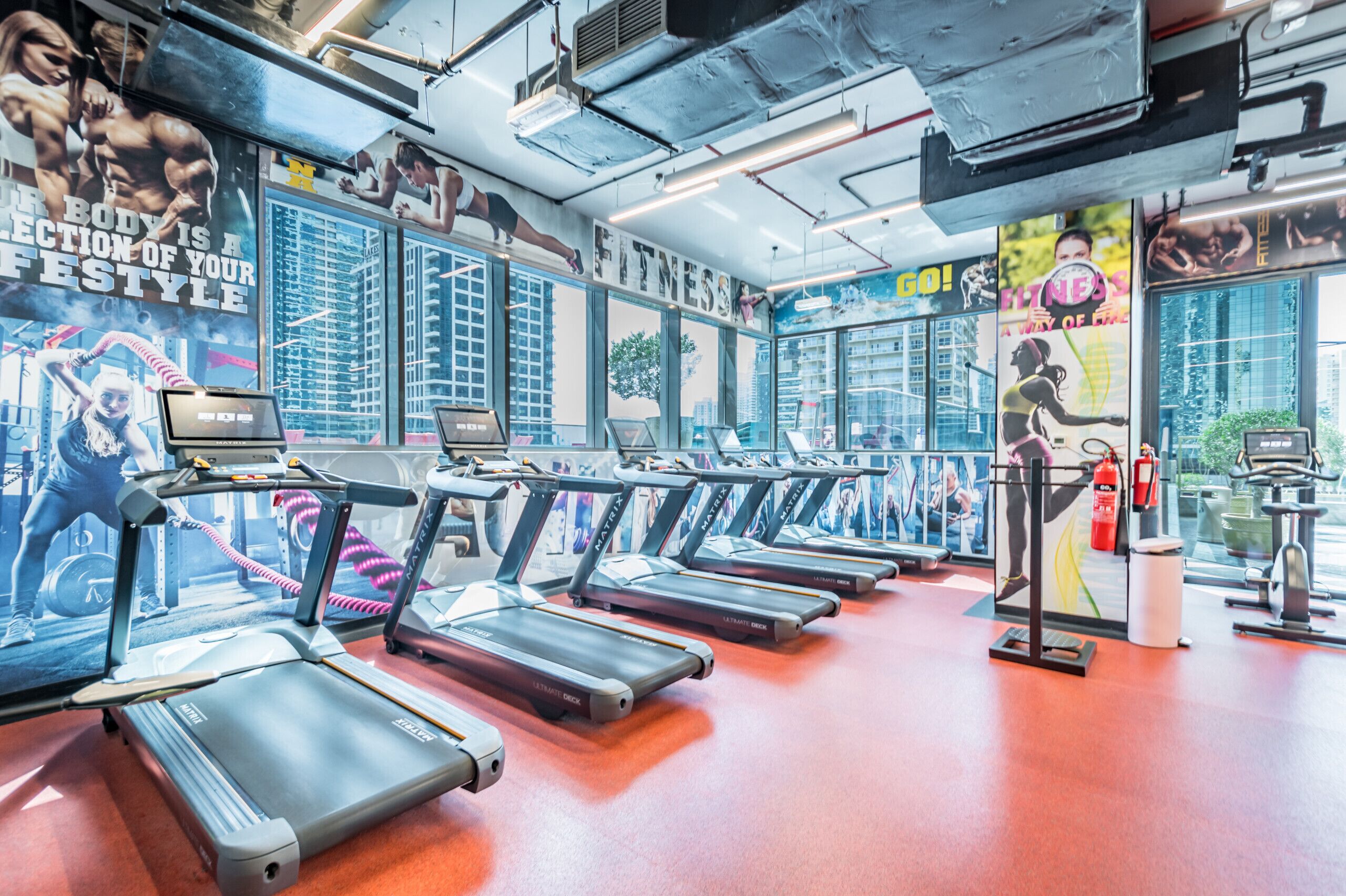 A gym with treadmills, exercise equipment, and motivational posters on the walls.