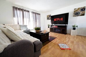 Una sala de estar con sofá, mesa de centro y televisor de pantalla plana montado en la pared.