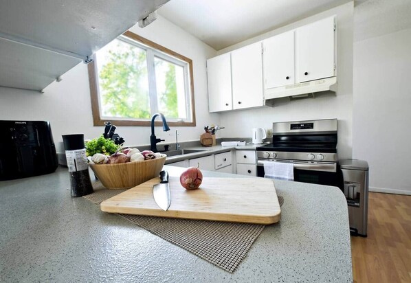 Una cocina moderna con una isla central, horno integrado y una ventana que proporciona luz natural.