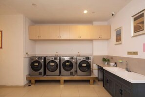 Un área de lavandería con cuatro lavadoras, un lavabo y armarios de madera.